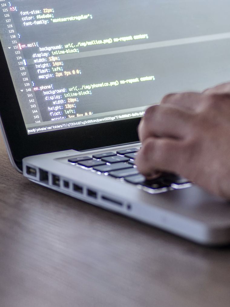 Ontwikkelaar werkt aan de code van een nieuwe website op een laptop