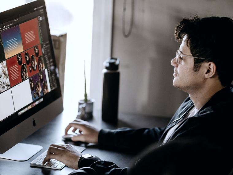 Designer werkt aan een website-ontwerp op een groot scherm